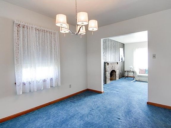 Dining room with access to living room and kitchen. Hardwood underneath carpet.
