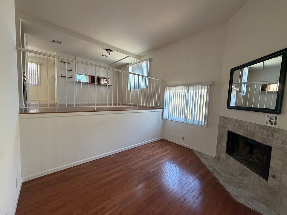 View of lower living area (or office), upper split level (living or dining are) visible. Kitchen has a pass through counter. Fireplace is non-operational