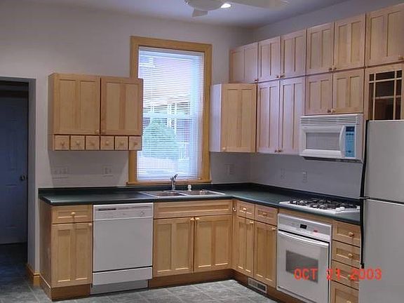 Kitchen with maple cabinetry and tile floor with stove top, oven, refrigerator, dishwasher, microwave, garbage disposal and ceiling fan. Powder room is behind kitchen by back door to deck and back yard is on left of picture.