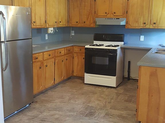 Kitchen in one section with new fridge, new floors and counter tops