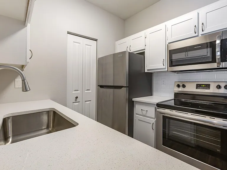 Experience culinary bliss in our sleek kitchen adorned with pristine white cabinets and modern stainless steel appliances