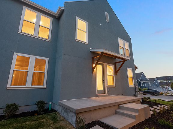 A modern, two-story house from the Contempo Collection with a gray exterior, large windows lit from