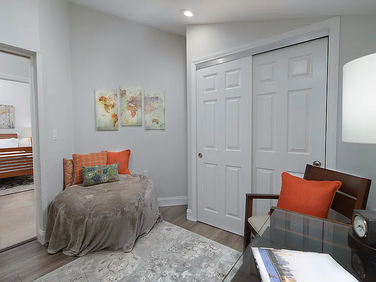 Second bedroom with storage closet and seating area and desk with chair.