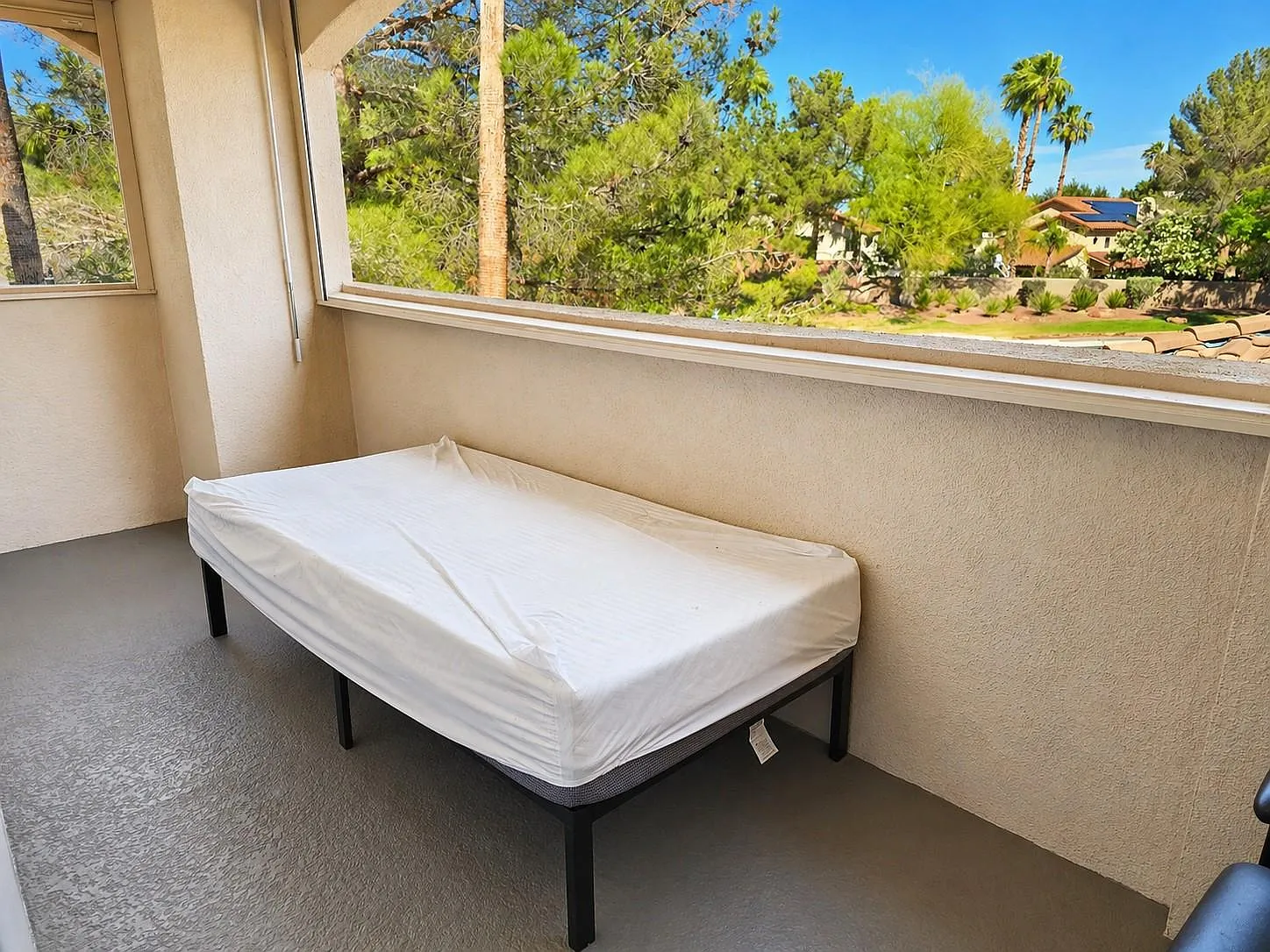 Covered outdoor balcony/patio with ample space for seating and an open railing that showcases treetop views.