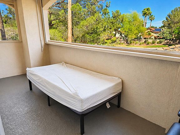 Covered outdoor balcony/patio with ample space for seating and an open railing that showcases treetop views.