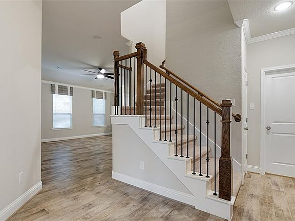 A view of the staircase that leads to the oversized game room and half bath upstairs, and peeking around into the family room.