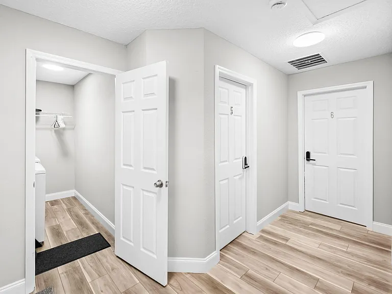 Wide hallway/entry area with durable wood-look flooring, multiple interior doors, and an adjacent laundry closet.