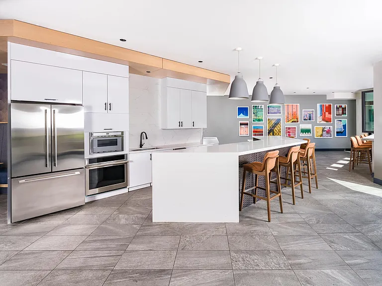 Club kitchen with island seating, stainless steel appliances, and vibrant local artwork.