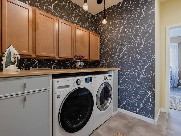 The laundry area is full service-- just outside the hall bathroom. To the left is a laundry hamper. There's an iron with a table top board and a clothes steamer. Washing machine is state of the art including quick wash cycles for those on the go.