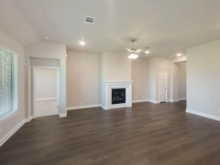 Spacious living area featuring wood-finish flooring, a white mantel fireplace, recessed lighting, and a ceiling fan