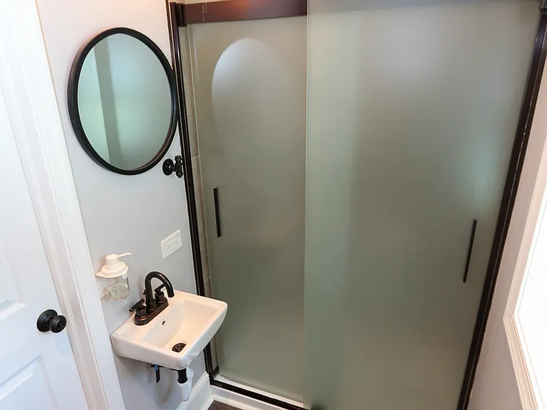 Newer tasteful bathroom with tiled shower and quaint exposed brick.