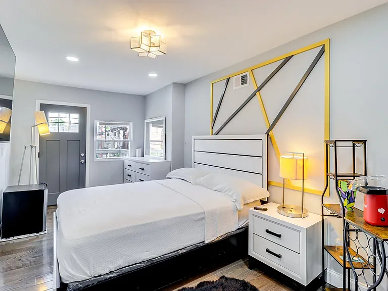 Furnished bedroom featuring a full bed, nightstand lighting, dresser storage, and a private exterior door with nearby windows