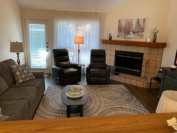 Living room featuring hardwood / wood-style floors, a tile fireplace, and lofted ceiling