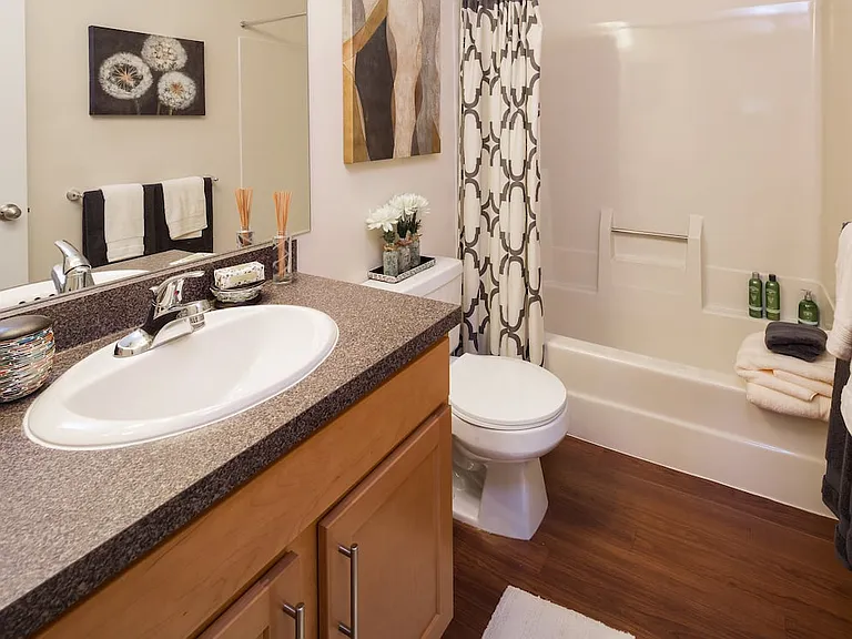 Classic Package bathroom with black speckled laminate countertops, maple cabinetry and hard surface flooring