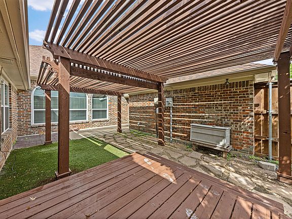 Covered pergola patio with paver seating area and private fenced yard access, ideal for outdoor dining or relaxing.