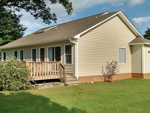 An outside vies from left/rear of home. Notice the solar hot water panels on the roof.