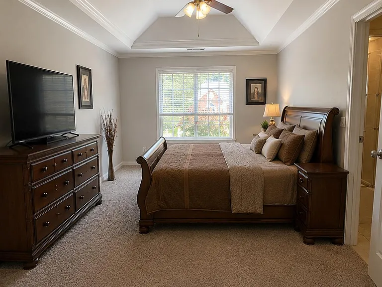 Spacious bedroom with vaulted ceiling, ceiling fan, large window, and ample space for a full bedroom set.