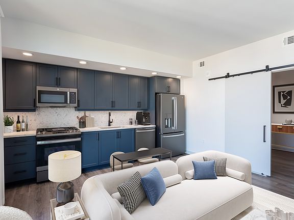 Studio Living Area and Kitchen featuring blue cabinets and marble-style backsplash and countertops.
