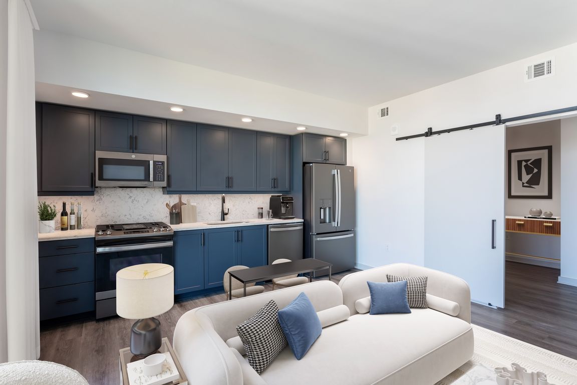 Studio Living Area and Kitchen featuring blue cabinets and marble-style backsplash and countertops.
