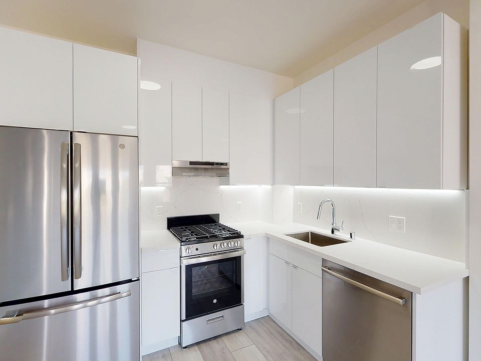 Kitchen with cabinets, marble-like countertop, gas stove, and stainless fridge