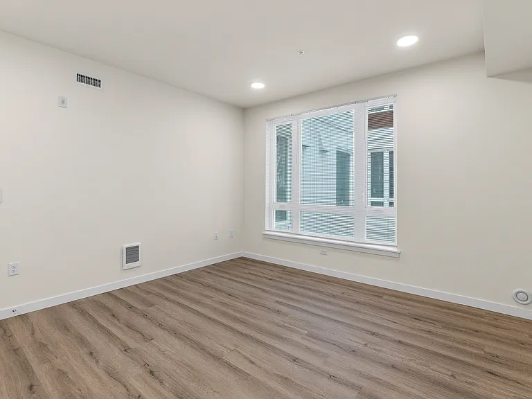 Seamless flow between the living area and kitchen, highlighted by wood-style flooring and recessed lighting Seamless flow between the living area and kitchen, highlighted by wood-style flooring and recessed lighting