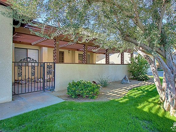 Gated front patio with slatted patio cover.