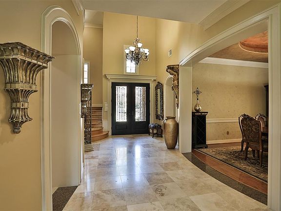 Upon entering you find a lovely corridor showcasing custom paint, beautiful floors, elegant archways with crown molding details, high ceilings, and ample lighting!