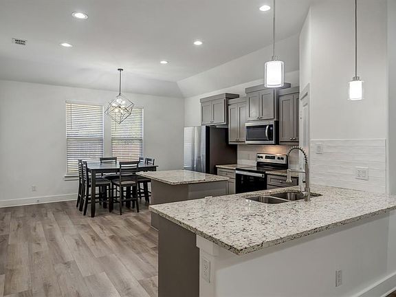 Kitchen with pendant lighting, kitchen peninsula, appliances with stainless steel finishes