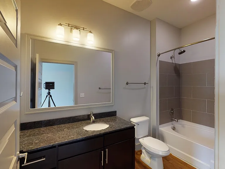 Apartment bathroom with wood-style flooring.