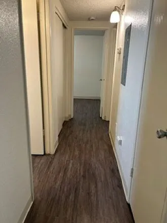 Hallway from living room to bedrooms with guest coat closet and linen closet