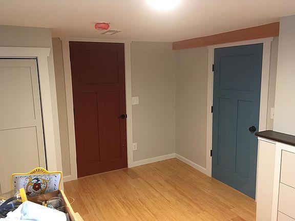 The bedroom includes a closet, a door to the shared laundry room (red door) a door into the living room (blue door) and a built-in dresser (drawers at right of photo).