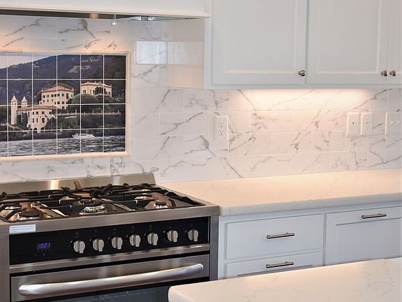 Top-of-the-line New appliances with under cabinet lighting and unique backsplash tile.