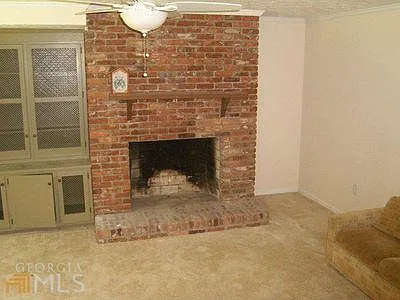 Basement activity room with fireplace and tall built in cabinet. To the left there is sliding glass door out to backyard and the boat dock and lake