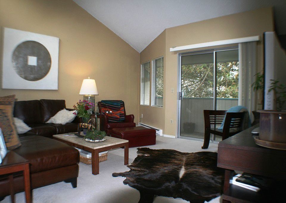 Living room w/ vaultlted ceilings, large windows and door to balcony