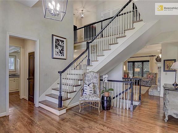 Grand staircase with hardwood steps leads the way to second floor of home also with hardwood landing.