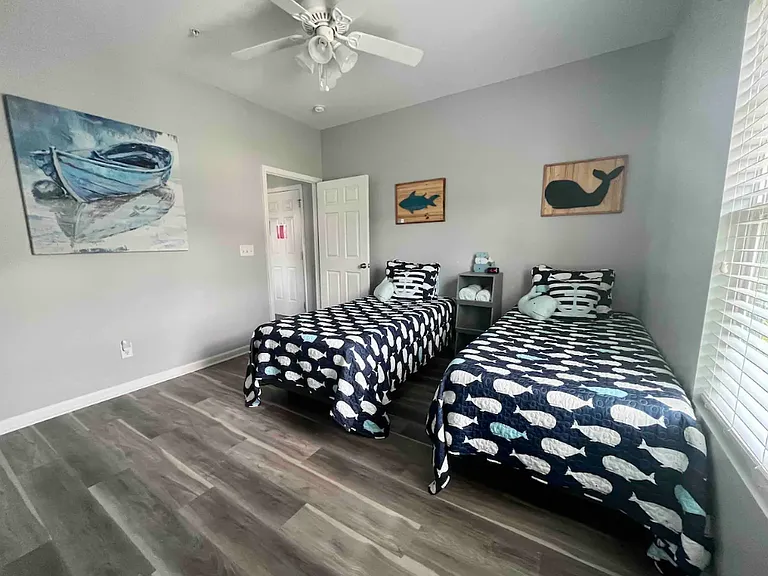 The third bedroom has two twin beds, two closets, a smart TV, small dresser, and ceiling fan.