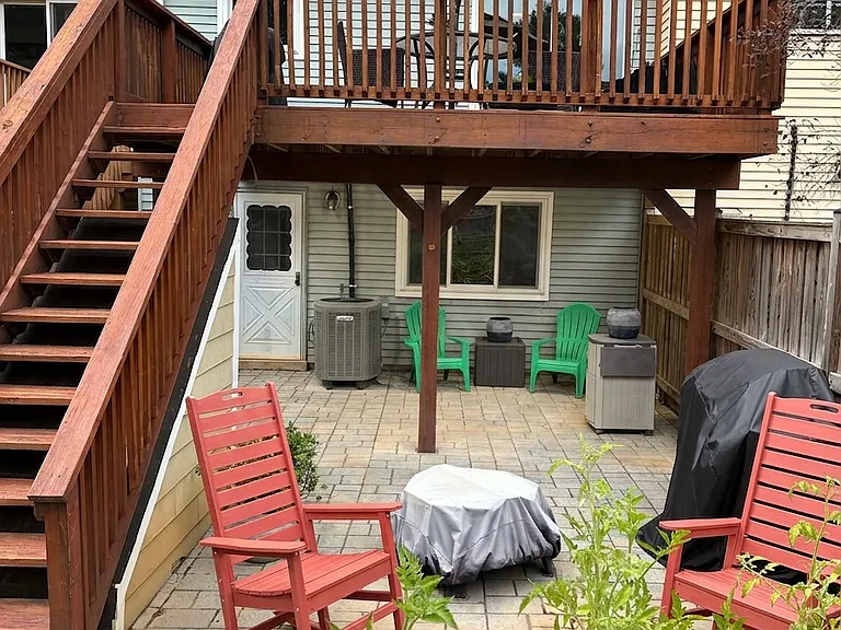 Private Outdoor Sanctuary: Custom stone paver patio with built-in French drain system to ensure quick drainage. Enjoy versatile outdoor living with cozy seating around the fire pit, a sheltered area under the deck, and direct stair access to the deck.