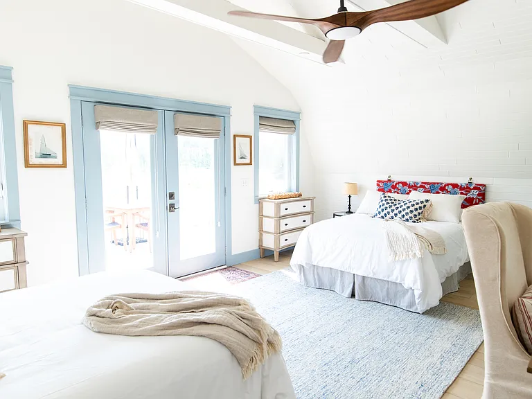 The second bedroom includes two full beds, two small dressers, a closet, a desk, and French doors that open out to the expansive back deck that overlooks vineyards.