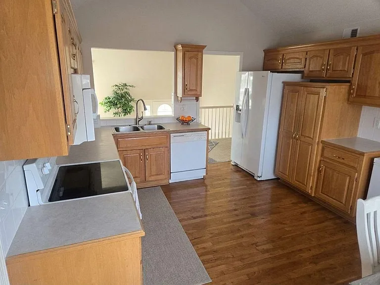 Functional kitchen with ample wood cabinetry, generous counter space, double-basin sink, and full-size appliances.