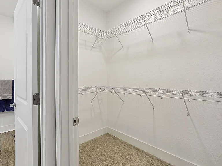 Spacious walk-in closet with modern wire shelving and soft carpeting, perfect for organized storage in a stylish apartment.
