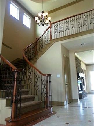  What a gorgeous view of your elegant wrought iron staircase, beautiful tile flooring with design with tall ceiling with beautiful light fixture.