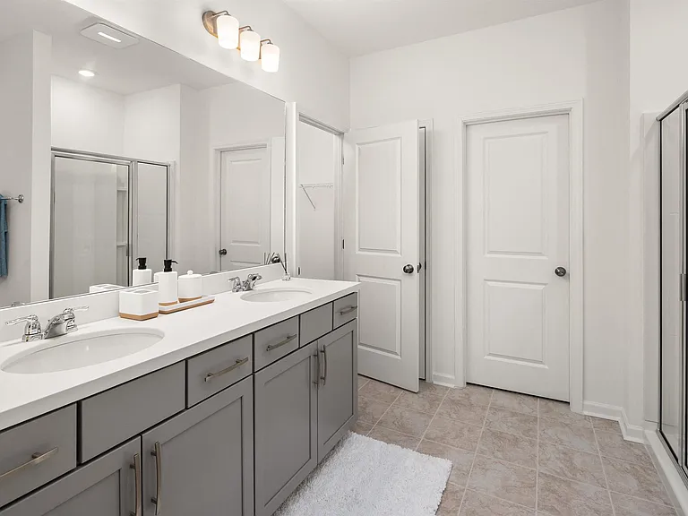 Primary bathroom with double vanity and walk-in shower .