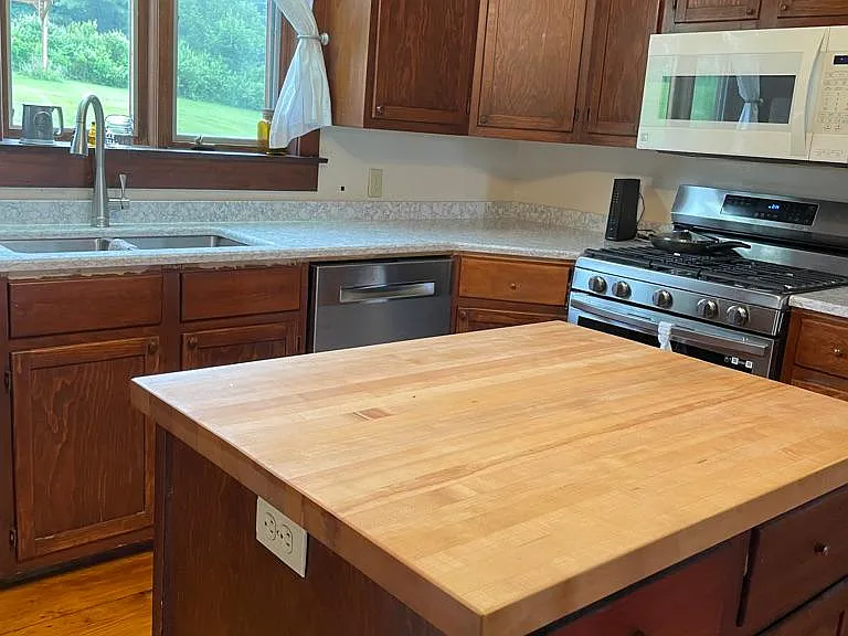 Kitchen Maple Butcher block, Stove Quartz countertops. View looking into backyard.