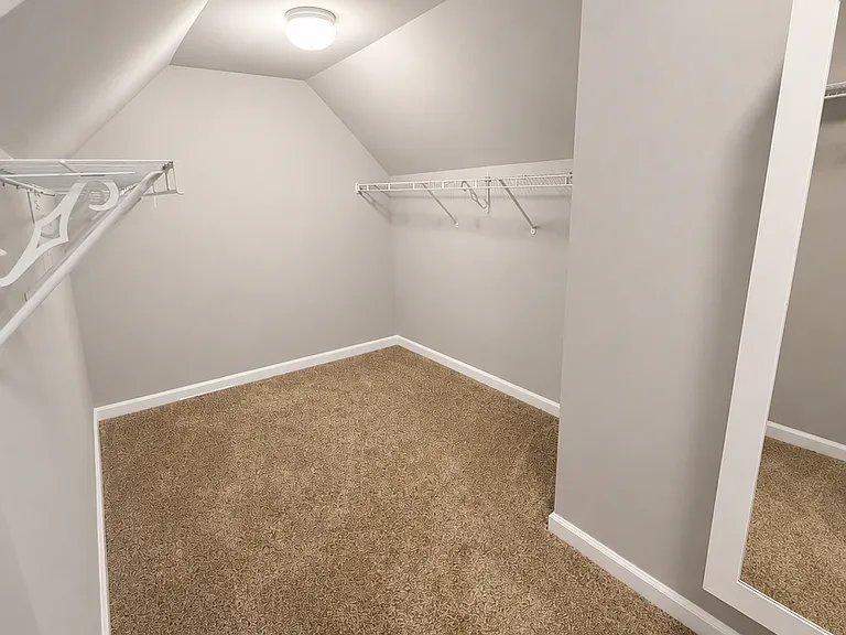 Oversized walk-in closet with built-in shelving and multiple hanging areas, providing exceptional storage and organization.