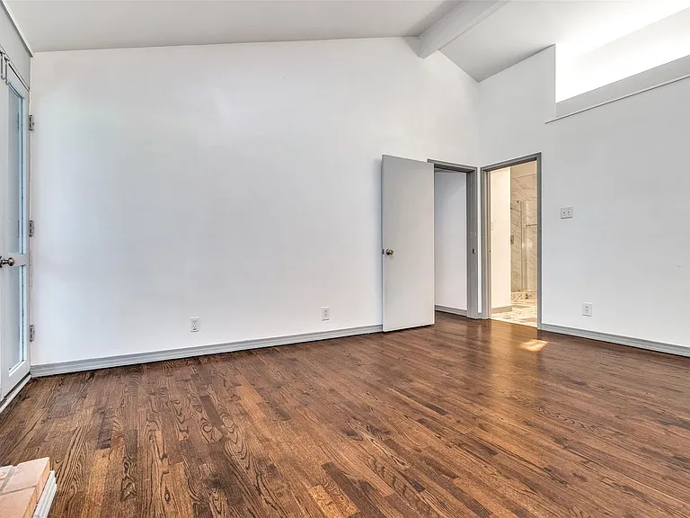 Spacious interior featuring rich wood-finish flooring, crisp white walls, and a vaulted ceiling