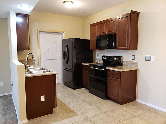 Upgraded kitchen with granite counters, electric cooktop range, built-in microwave, refrigerator. Barn door reveals the laundry area with full-size washer and dryer.