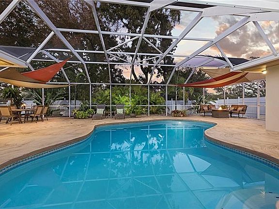 Huge bird caged screened pool.  White vinyl fencing and tropical landscape provides ambiance and privacy.