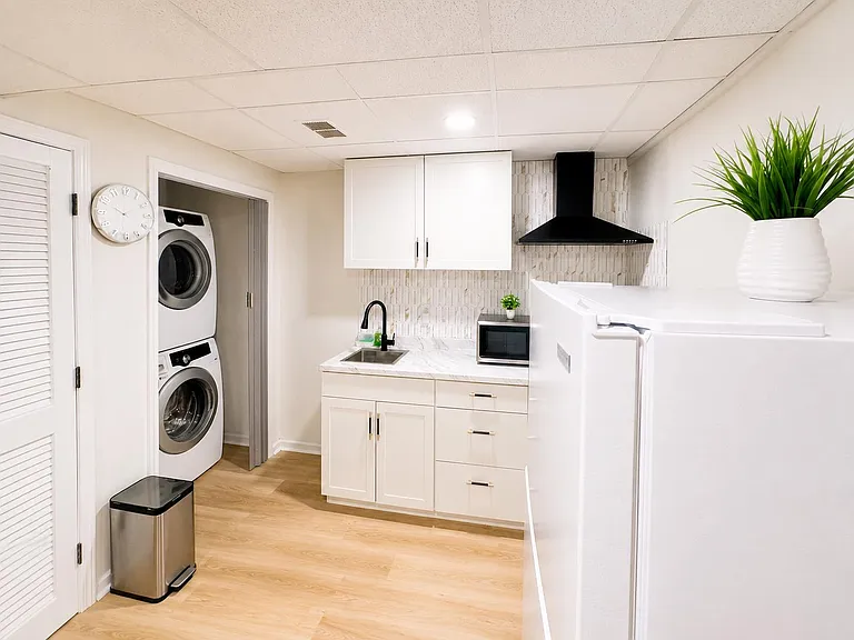 Well-appointed kitchenette with ample cabinetry, sink, microwave, and vent hood, plus convenient in-unit stacked laundry.