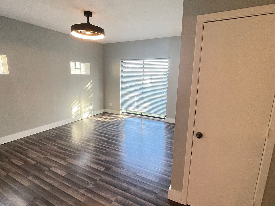 Light-filled living/sleeping area featuring glass-block windows, ceiling fan and gleaming vinyl plank flooring.