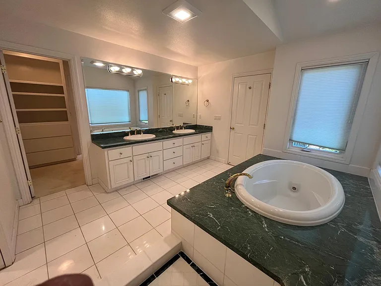 In-suite primary bathroom is tastefully-appointed with dual sinks, Jacuzzi tub and shower stall.
